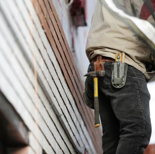 Close-up of a construction worker with hammer and tools, focused on the job.